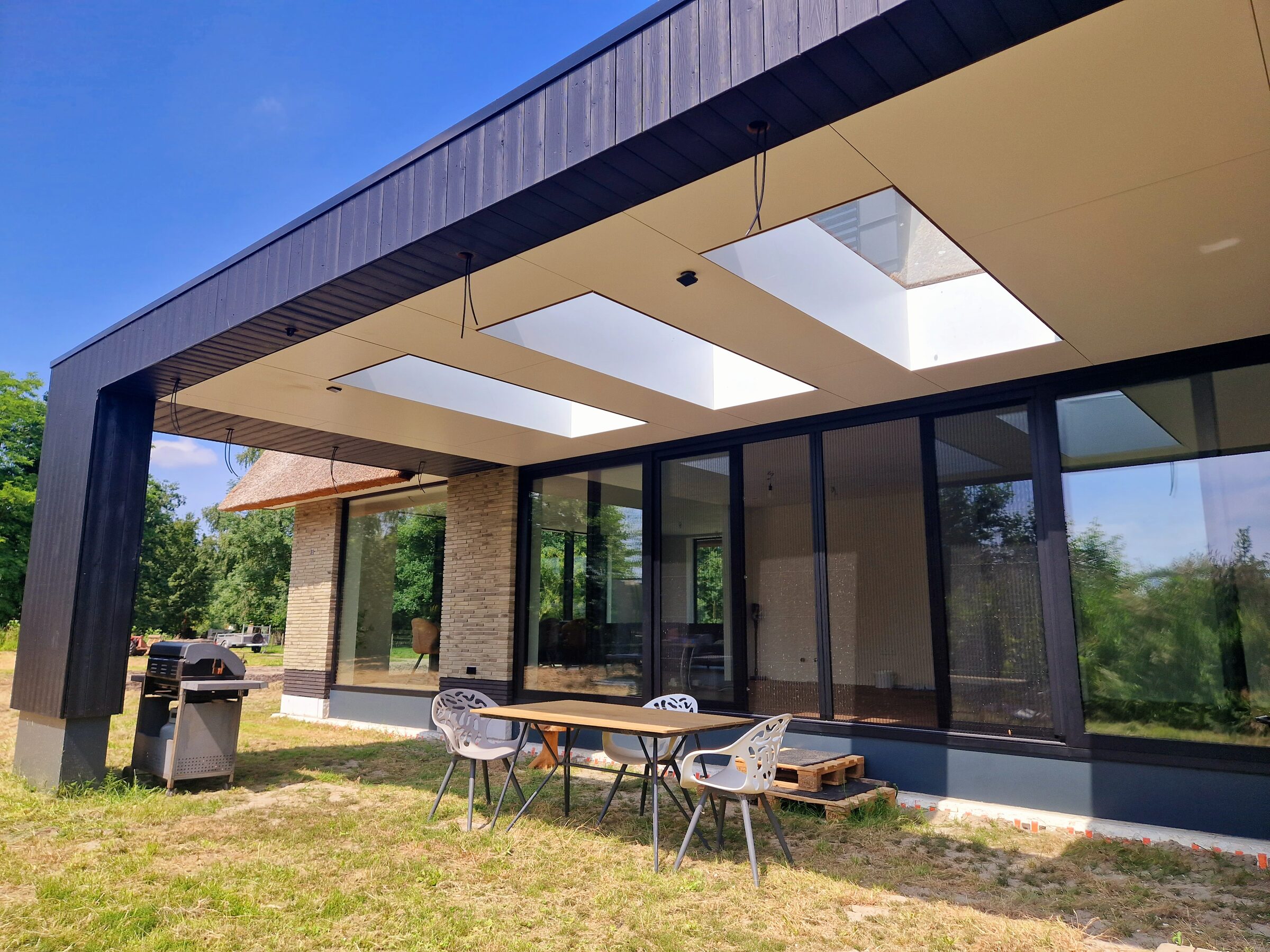 Villa met rieten dak, gebouwd door LBH Bouw: overkapping met daklichten en terras